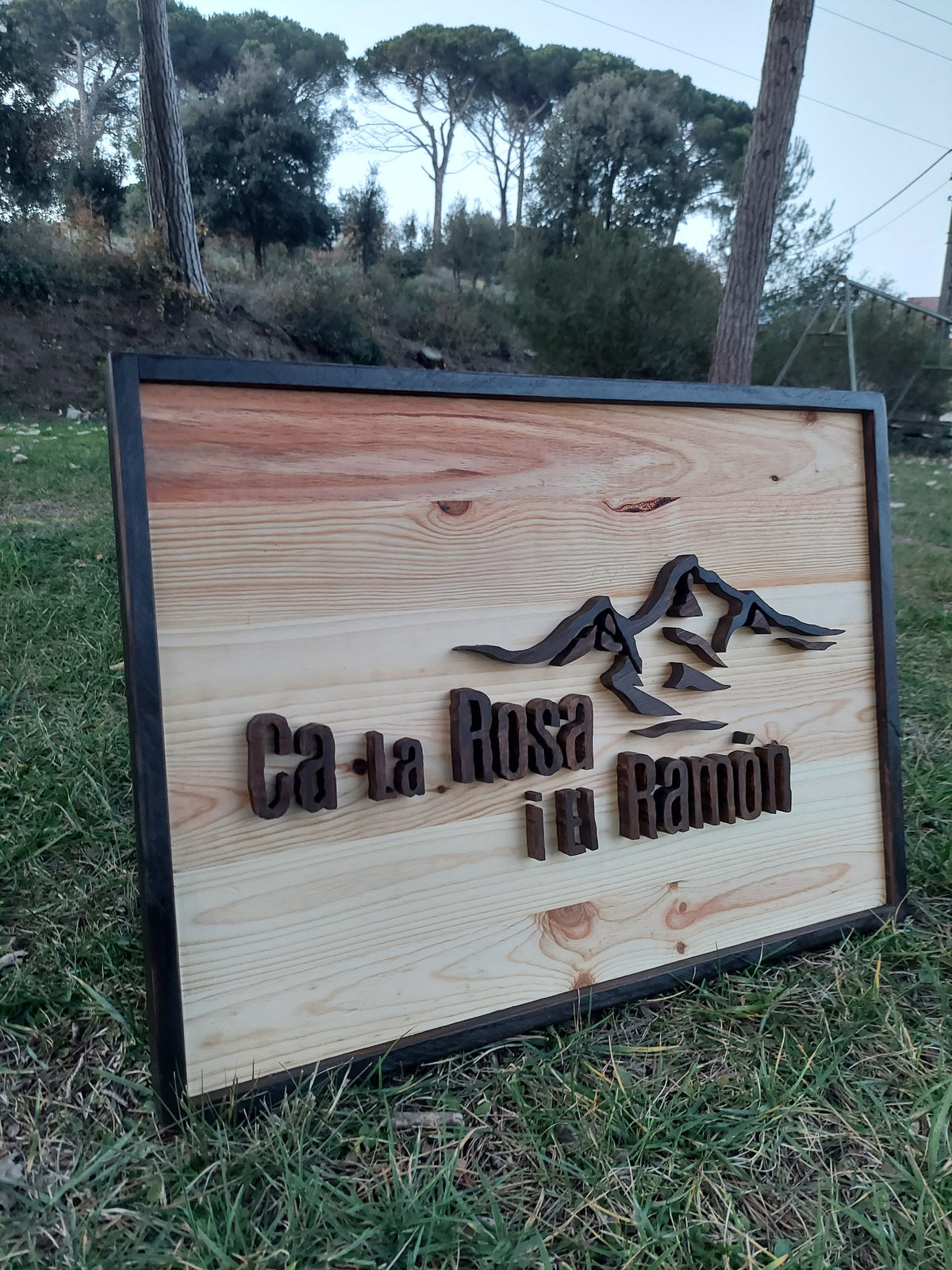 Letrero de madera con paisaje de montañas en la pared