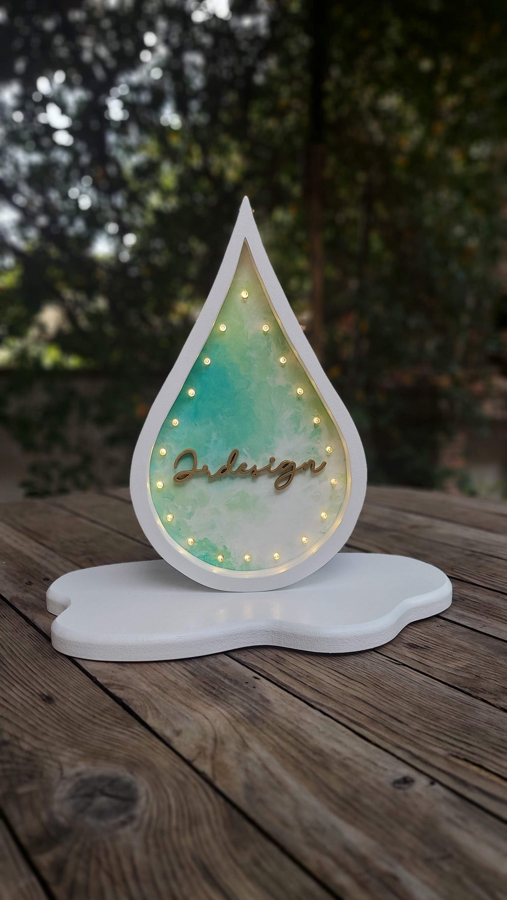 Letrero de madera en forma de gota con nombre iluminado